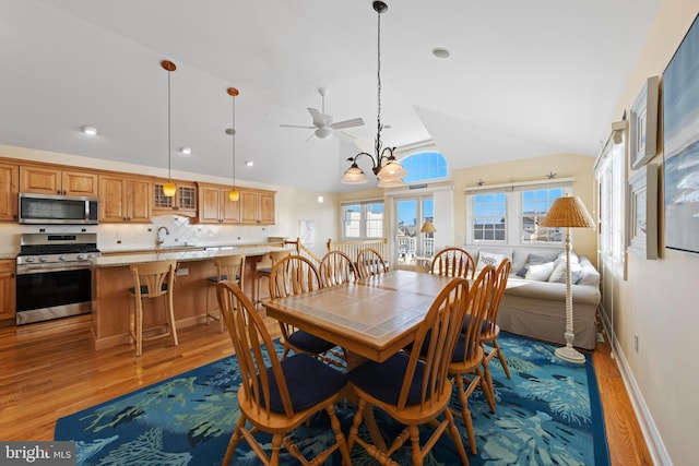 dining area with vaulted ceiling, sink, a notable chandelier, and light wood-type flooring