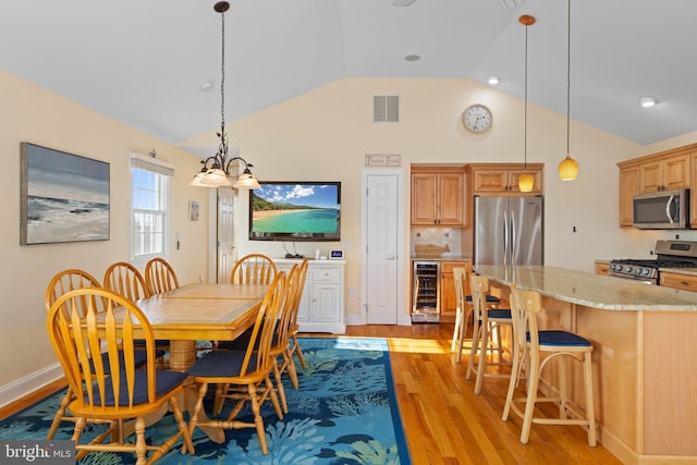 dining area featuring wine cooler, a notable chandelier, vaulted ceiling, and light wood-type flooring