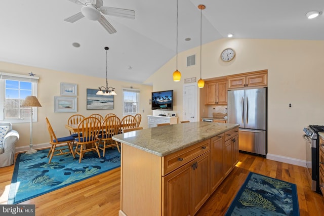 kitchen featuring stainless steel appliances, light stone countertops, a center island, and hanging light fixtures