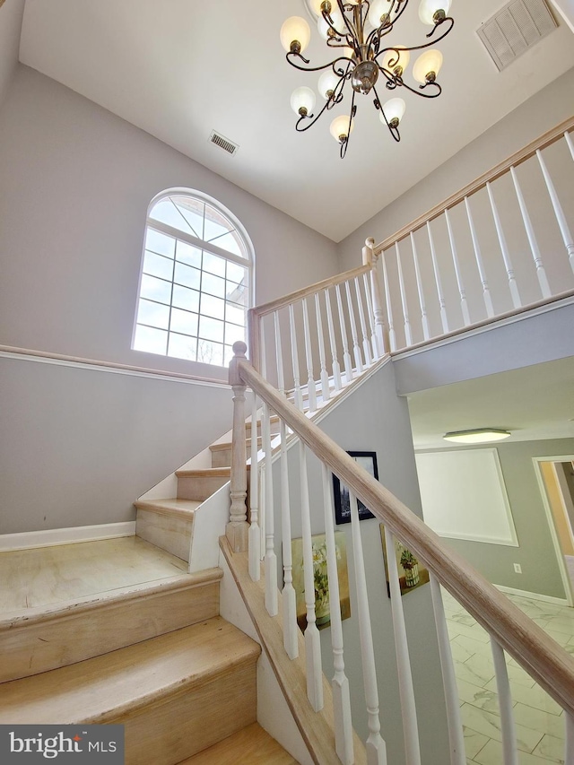 stairway featuring a high ceiling and a chandelier