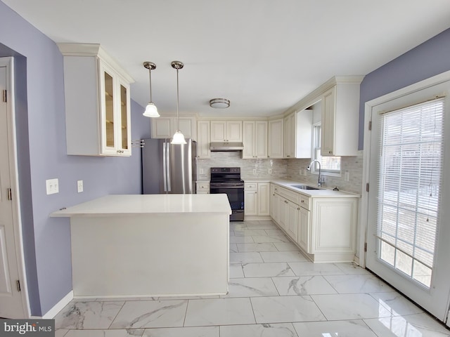 kitchen featuring electric stove, sink, stainless steel fridge, hanging light fixtures, and backsplash