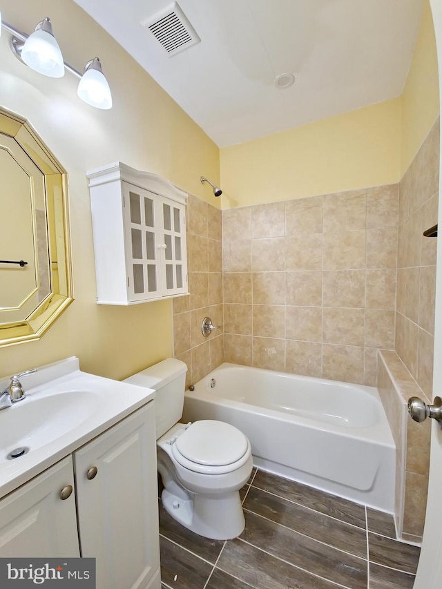 full bathroom with tiled shower / bath combo, vanity, and toilet