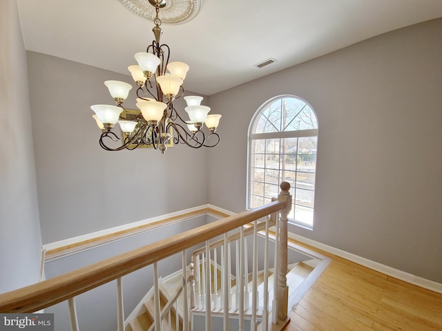 hall featuring wood-type flooring, plenty of natural light, and an inviting chandelier