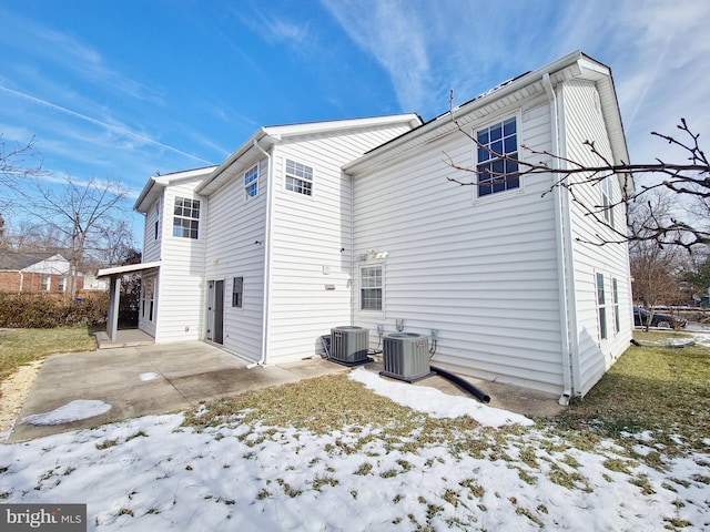 snow covered rear of property featuring a patio and cooling unit