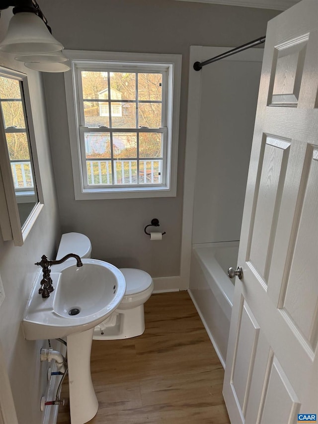 bathroom with shower / washtub combination, hardwood / wood-style floors, and toilet