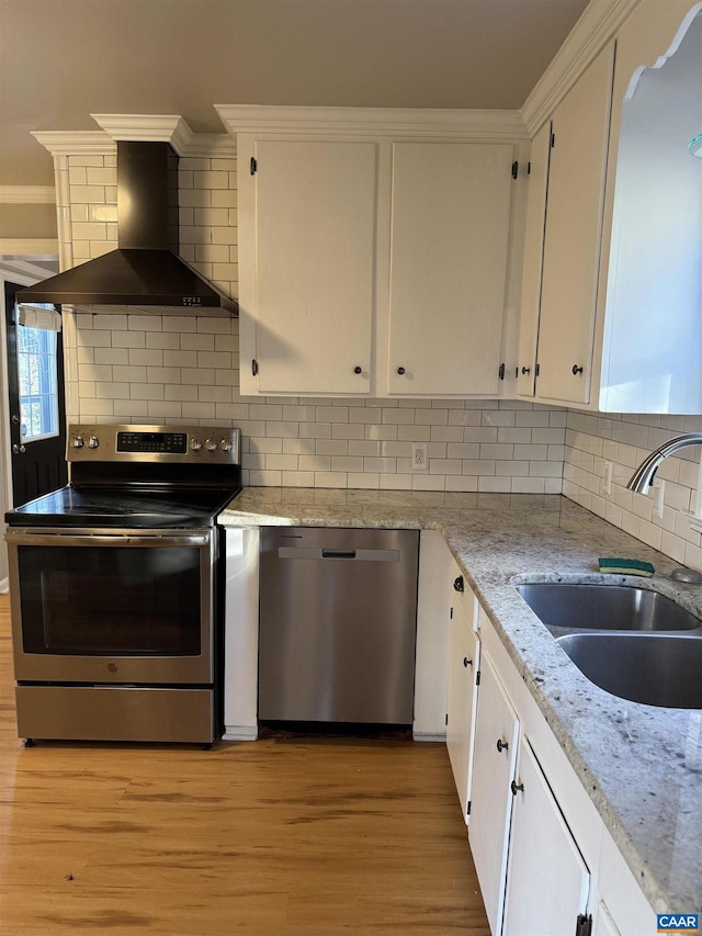 kitchen featuring white cabinetry, sink, backsplash, stainless steel appliances, and wall chimney range hood