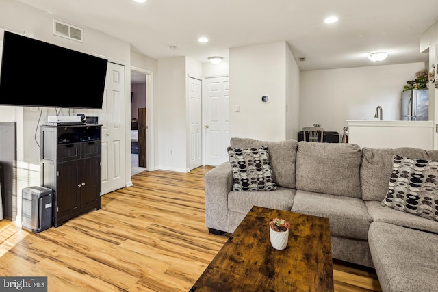 living room featuring sink and light hardwood / wood-style floors