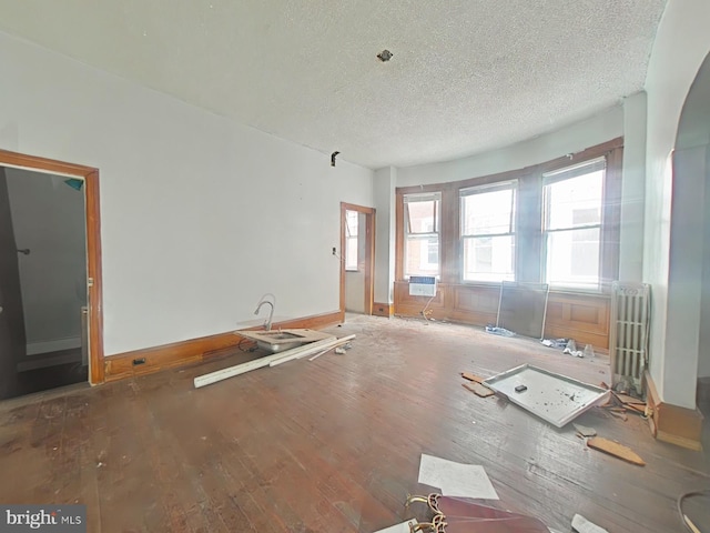 unfurnished room with hardwood / wood-style flooring, radiator, and a textured ceiling