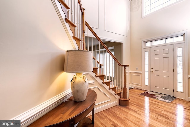 entryway with a towering ceiling and light wood-type flooring