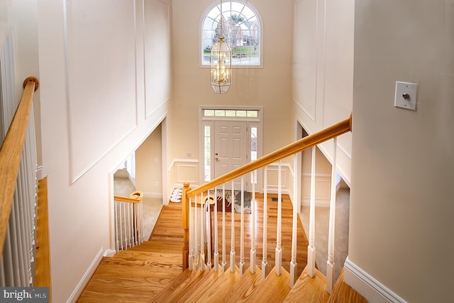 stairs featuring a towering ceiling, a chandelier, and hardwood / wood-style floors