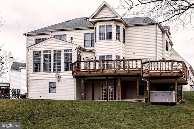 back of property with a yard, a hot tub, and a deck