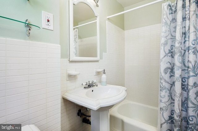 bathroom with tile walls and shower / bath combo with shower curtain