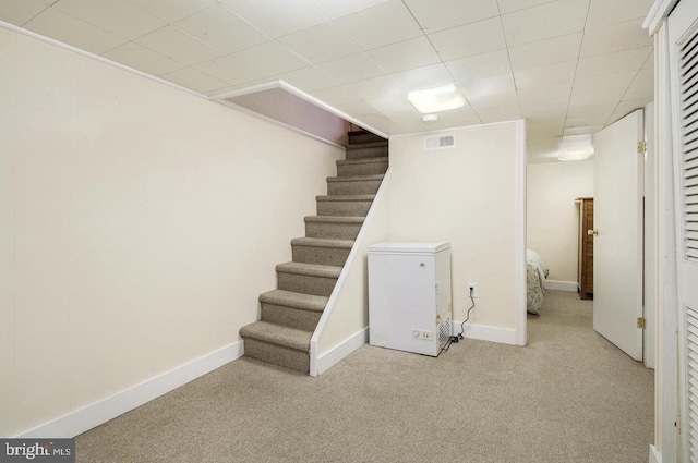 basement featuring light carpet and fridge