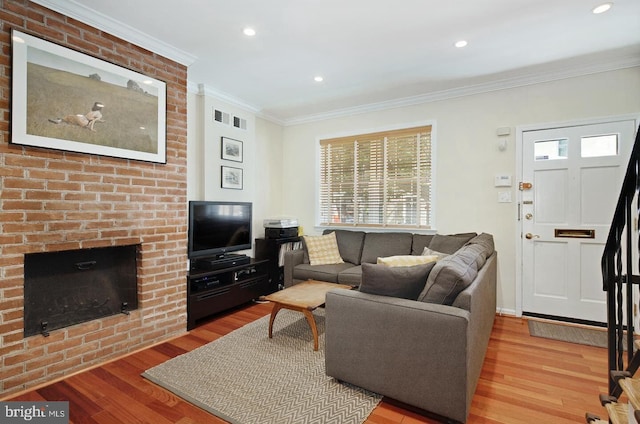 living room featuring ornamental molding, a brick fireplace, and light wood-type flooring