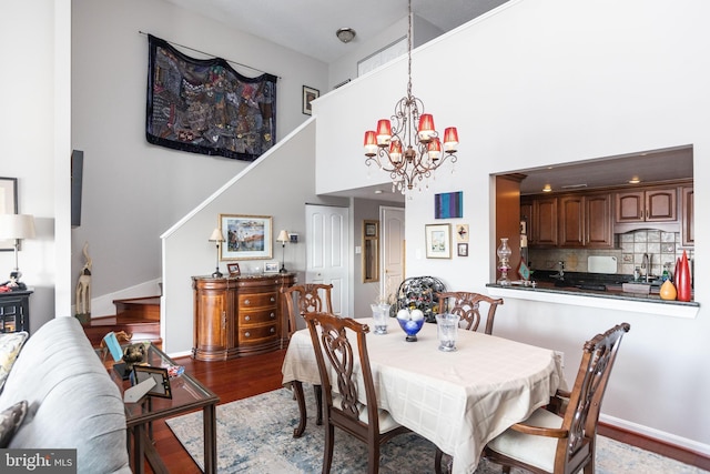 dining room featuring a high ceiling, sink, an inviting chandelier, and light hardwood / wood-style flooring