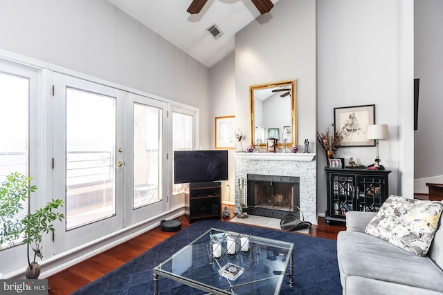 living room with french doors, a stone fireplace, high vaulted ceiling, dark hardwood / wood-style floors, and ceiling fan