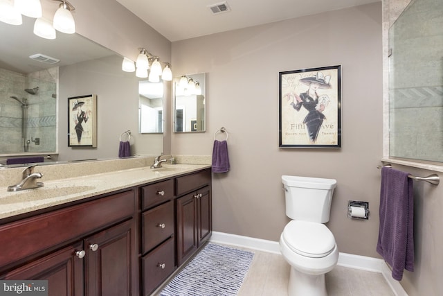 bathroom featuring vanity, a tile shower, and toilet