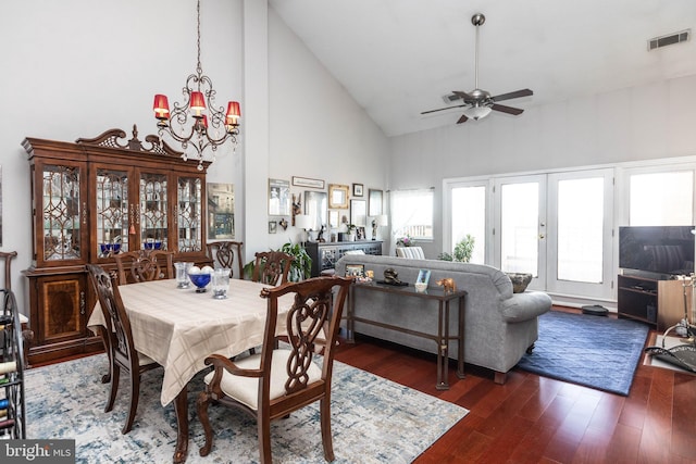 dining space with dark hardwood / wood-style flooring, ceiling fan with notable chandelier, high vaulted ceiling, and french doors