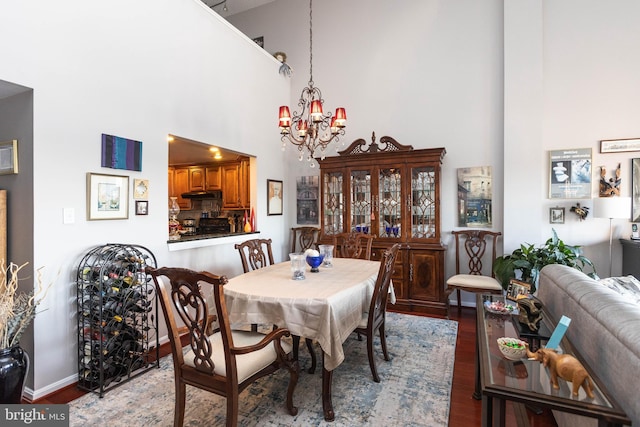 dining space with an inviting chandelier, a towering ceiling, and light hardwood / wood-style floors