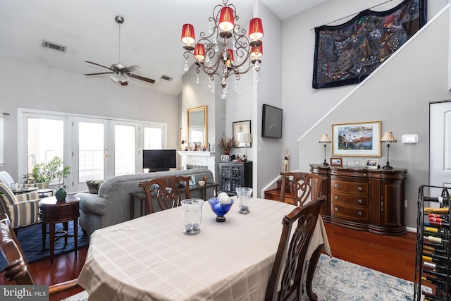 dining space featuring ceiling fan with notable chandelier, a towering ceiling, hardwood / wood-style floors, and french doors