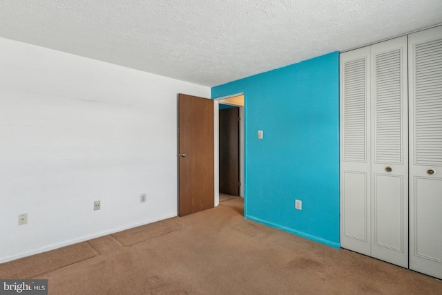 unfurnished bedroom with light colored carpet, a textured ceiling, and a closet