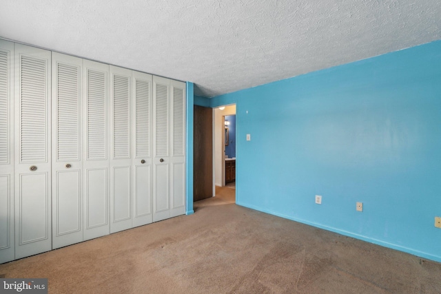 unfurnished bedroom with light carpet, a closet, and a textured ceiling