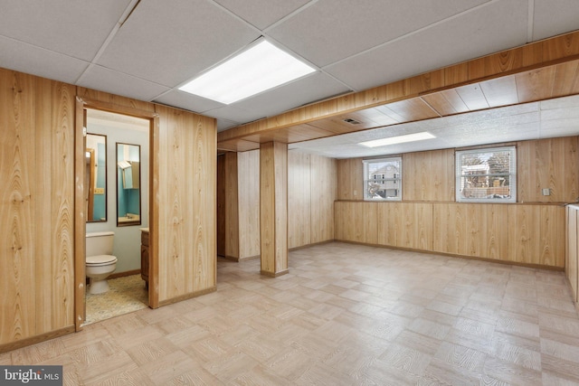 basement with wooden walls and a drop ceiling