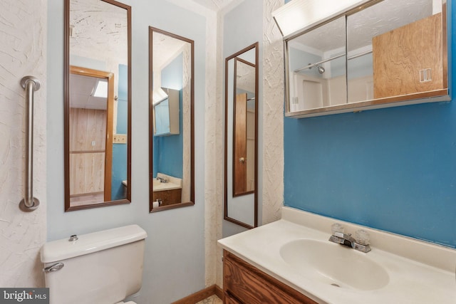 bathroom featuring vanity, a shower, a textured ceiling, and toilet