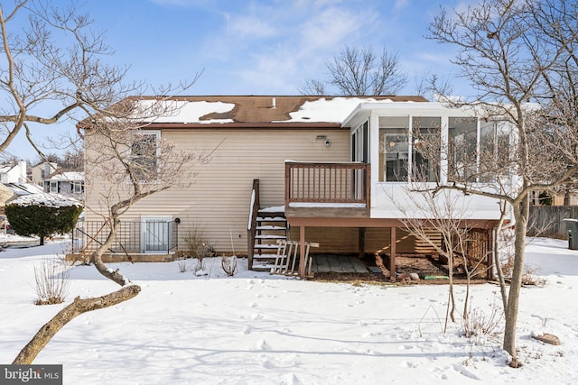 snow covered house featuring a sunroom