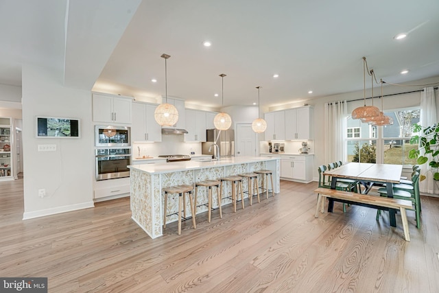 kitchen featuring pendant lighting, white cabinets, a spacious island, and appliances with stainless steel finishes