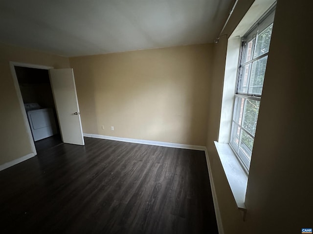 unfurnished room featuring washer / clothes dryer, plenty of natural light, and dark wood-type flooring