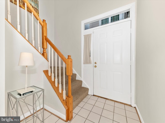 entryway featuring stairway, light tile patterned flooring, and baseboards