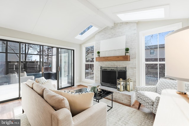 living room featuring a fireplace, lofted ceiling with skylight, and light hardwood / wood-style floors