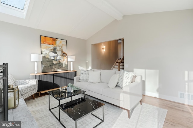 living room featuring vaulted ceiling with skylight and light wood-type flooring