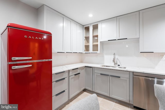 kitchen with gray cabinets, refrigerator, dishwasher, sink, and light stone countertops