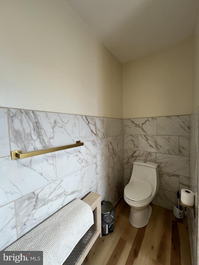 bathroom featuring hardwood / wood-style floors, tile walls, and toilet