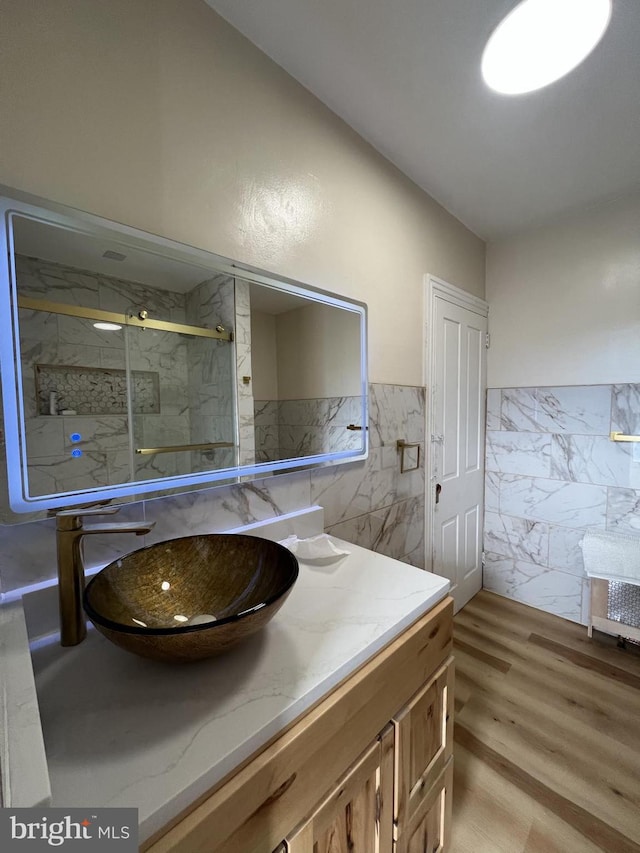 bathroom featuring vanity, hardwood / wood-style floors, tile walls, and a shower with shower door