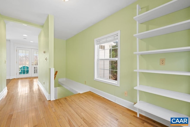 hallway with light hardwood / wood-style flooring, plenty of natural light, and french doors