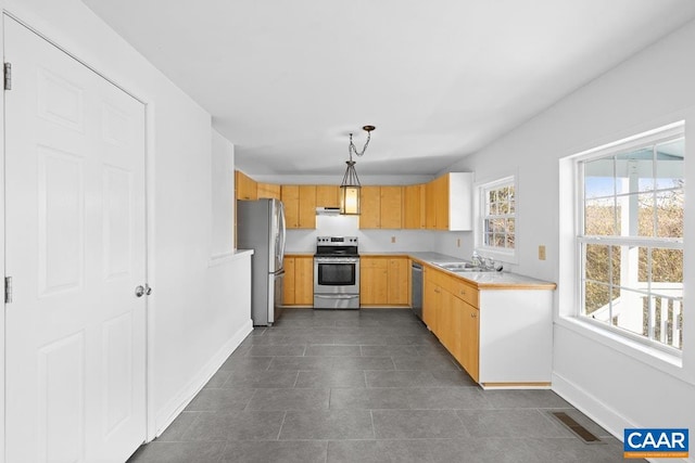 kitchen with pendant lighting, sink, stainless steel appliances, and light brown cabinets