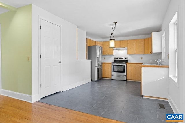 kitchen with hanging light fixtures, appliances with stainless steel finishes, sink, and light brown cabinetry