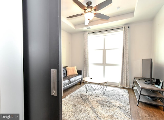 sitting room featuring ceiling fan, a tray ceiling, and hardwood / wood-style floors