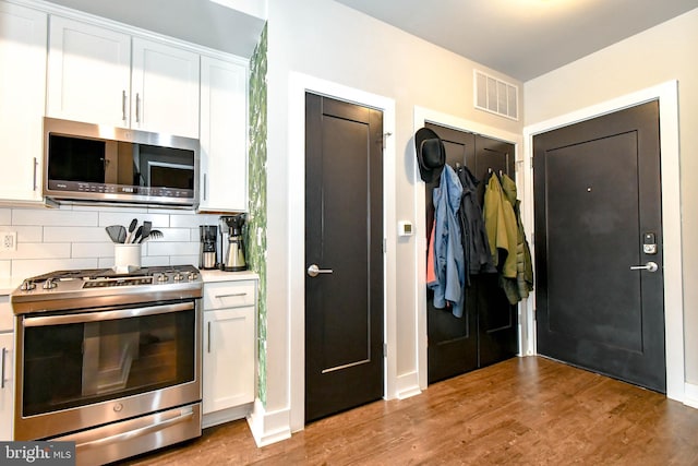 kitchen featuring hardwood / wood-style flooring, stainless steel appliances, decorative backsplash, and white cabinets