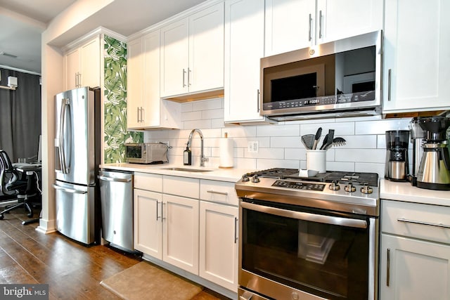 kitchen with appliances with stainless steel finishes, tasteful backsplash, white cabinetry, sink, and dark wood-type flooring