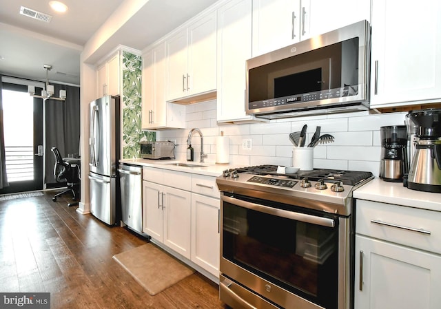 kitchen with appliances with stainless steel finishes, sink, decorative backsplash, and white cabinets