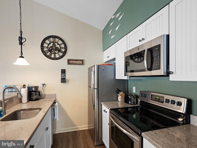 kitchen featuring sink, vaulted ceiling, pendant lighting, stainless steel appliances, and white cabinets