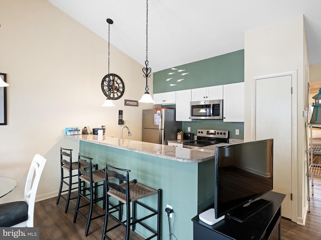 kitchen with a kitchen bar, white cabinetry, appliances with stainless steel finishes, pendant lighting, and light stone countertops