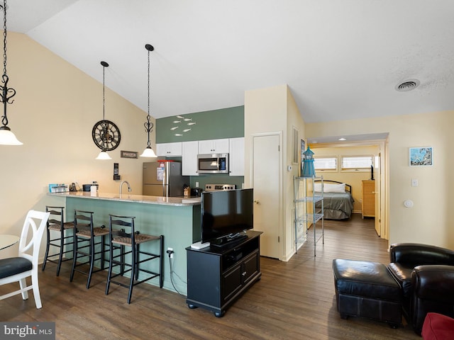 kitchen featuring hanging light fixtures, a kitchen breakfast bar, white cabinets, and appliances with stainless steel finishes