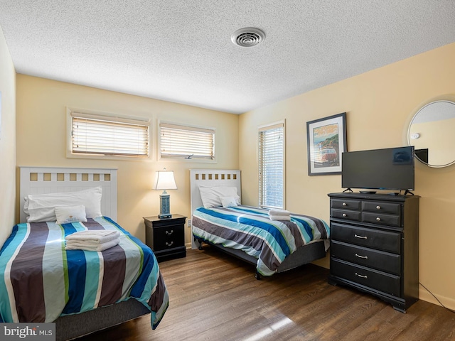 bedroom with dark hardwood / wood-style floors and a textured ceiling