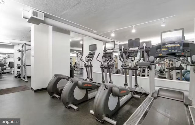 exercise room featuring track lighting and a textured ceiling