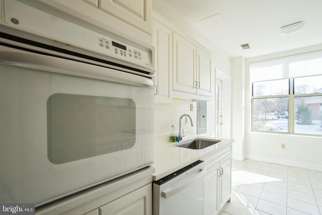 kitchen featuring white cabinetry, sink, light tile patterned flooring, and white appliances